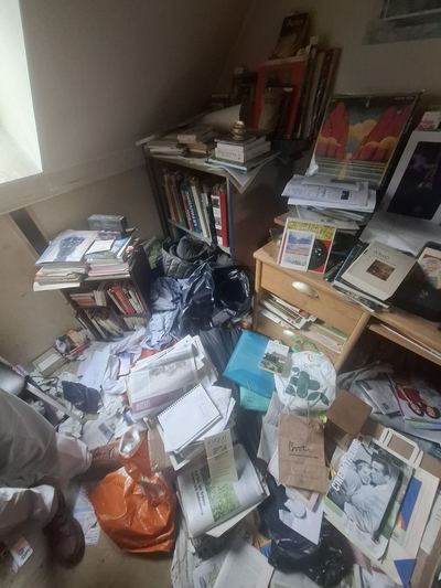 Bibliothèque débordante, sol recouvert de livres et de sacs