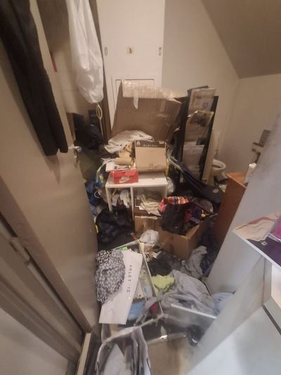 Chambre inaccessible, accumulation de papiers, sacs et objets sur toute la surface