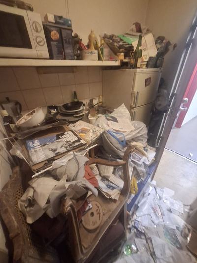 Cuisine en situation de syndrome de Diogène : plan de travail et sol recouverts