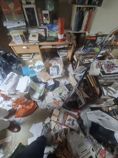 Séjour occupe par des centaines de livres et de revues empilés au sol
