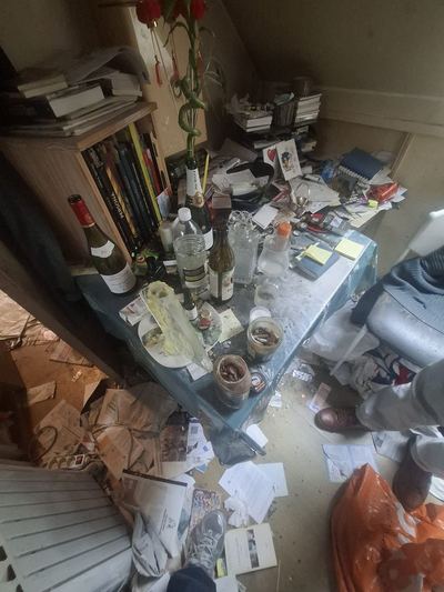 Table recouverte de bouteilles, de papiers et de vaisselle sale
