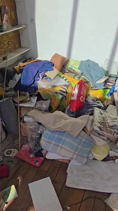 Amoncellement de vêtements, sacs et textiles au sol avant évacuation