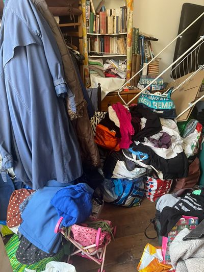 Chambre où les vêtements et les sacs recouvrent le plancher sur toute la surface