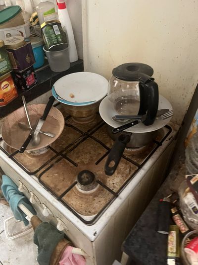Cuisinière à gaz couverte de vaisselle sale, grilles et émail encrassés
