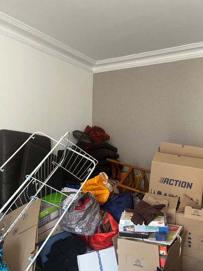 Pièce encombrée de cartons, de sacs et de mobilier, plafond mouluré intact