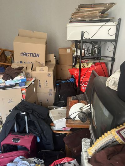 Séjour saturé de cartons, valises et mobilier empilés jusqu'à mi-hauteur