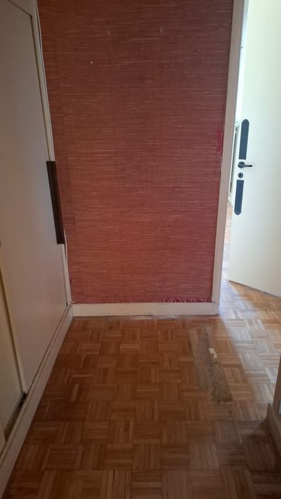 Entrée du même appartement après débarras complet : sol nu et murs dégagés