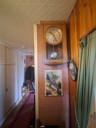 Couloir d'appartement avant débarras : horloge murale, tableau et tapis